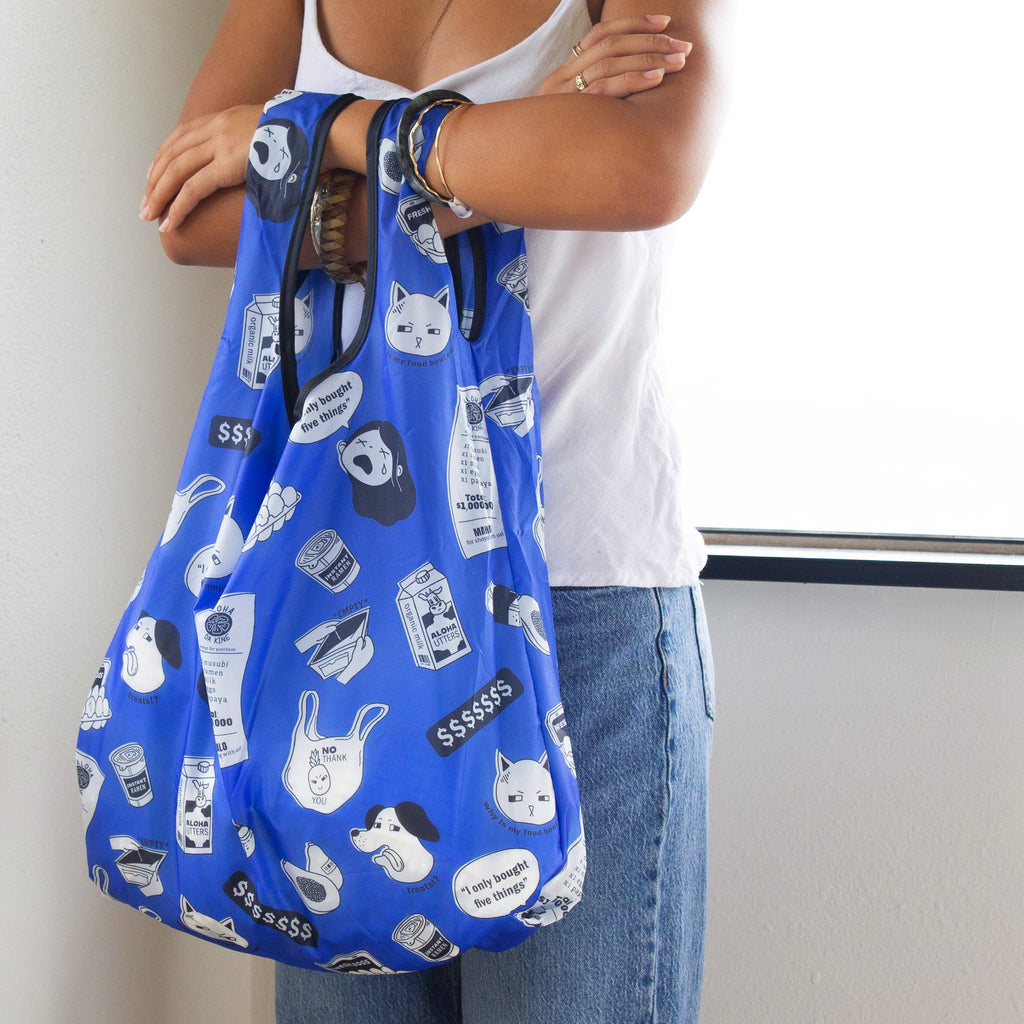 Person holding a blue reusable bag with dog-themed prints against a plain background